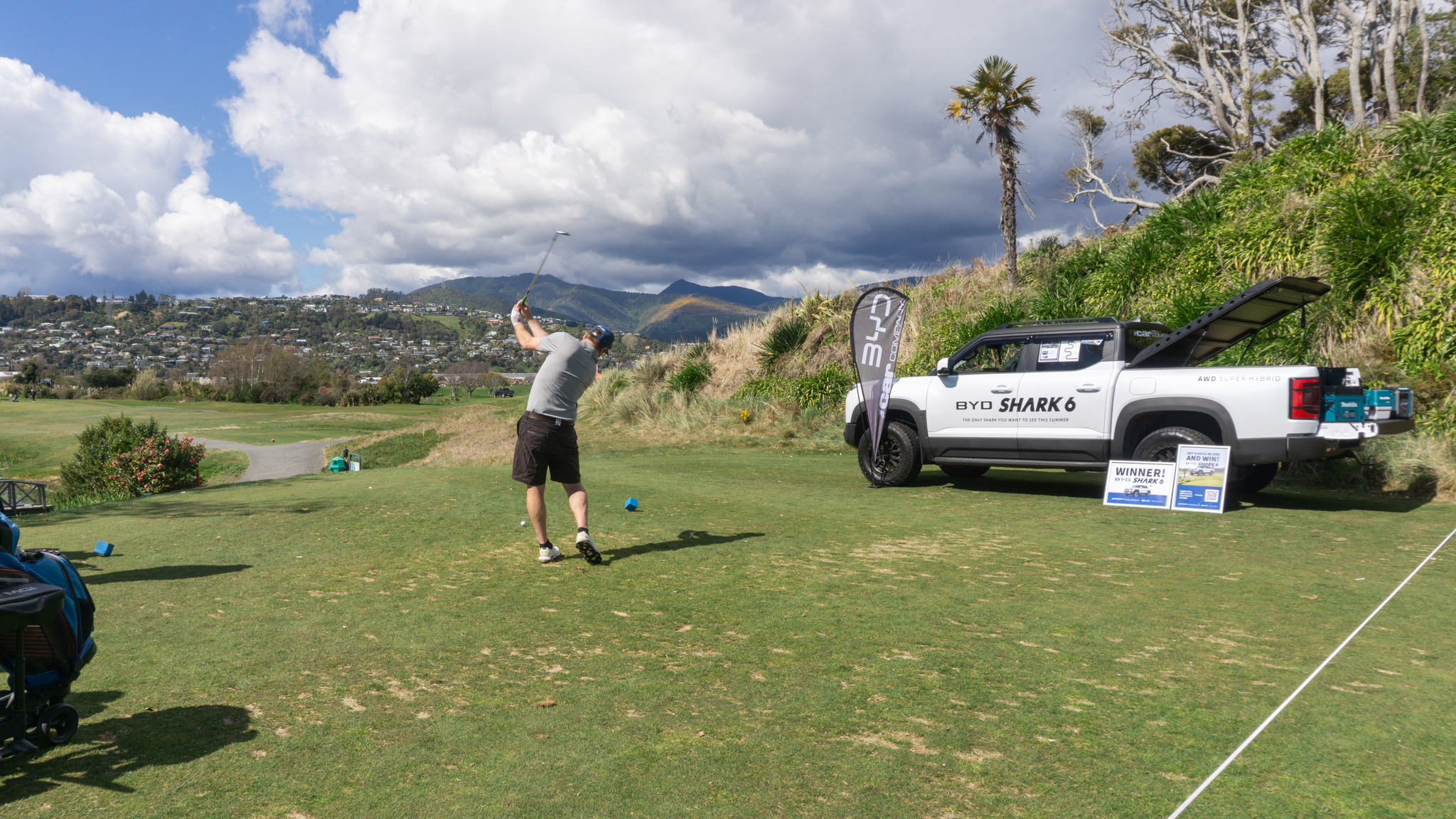 Golfer teeing off next to BYD Shark 6